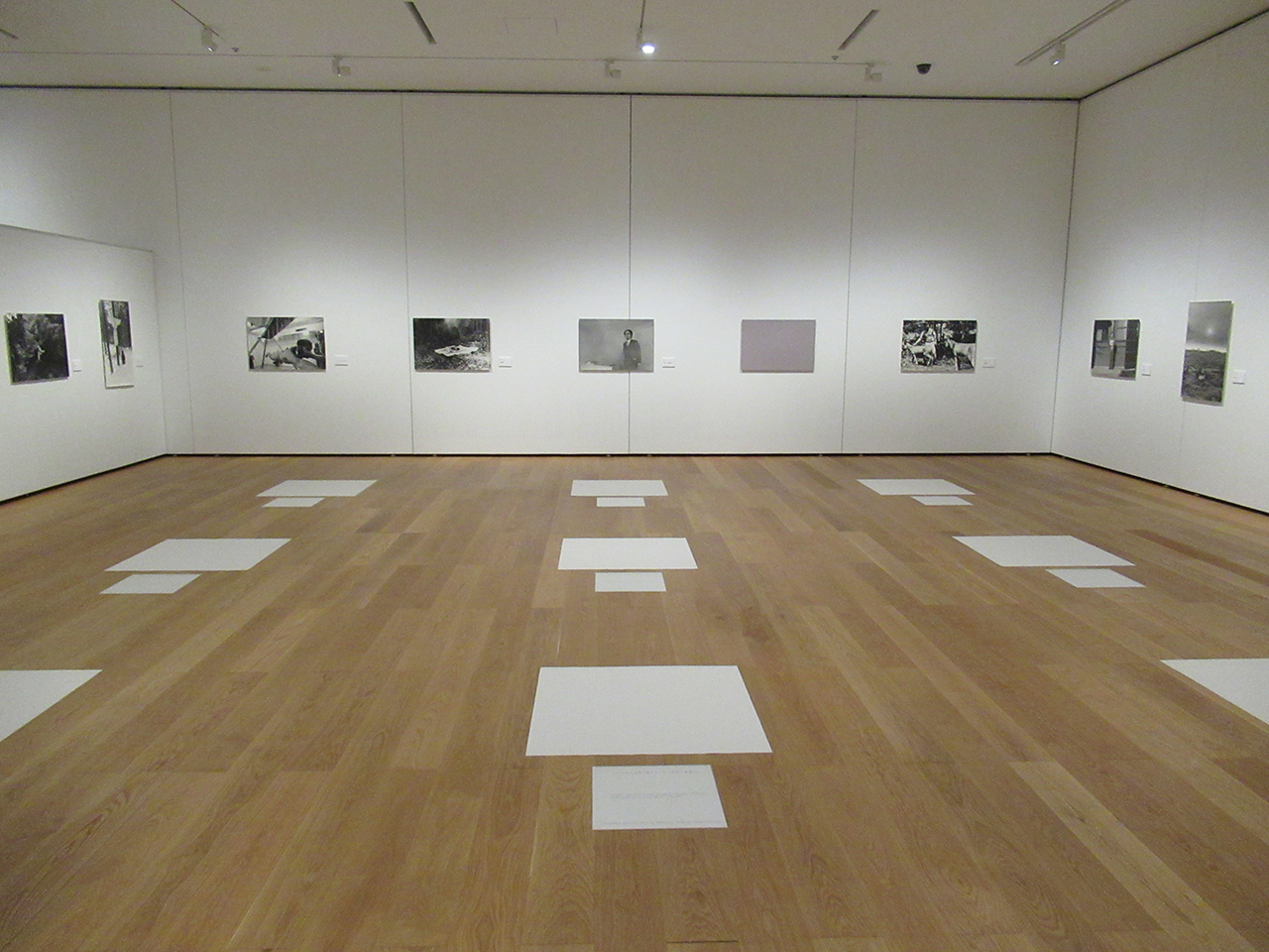 サンパウロ・ビエンナーレを再現した「九想の室」。床に白紙と「この白き紙を水と観ぜよ」などと書かれた紙が9組置かれ、壁にはニルヴァーナ・グループの活動写真が飾られている