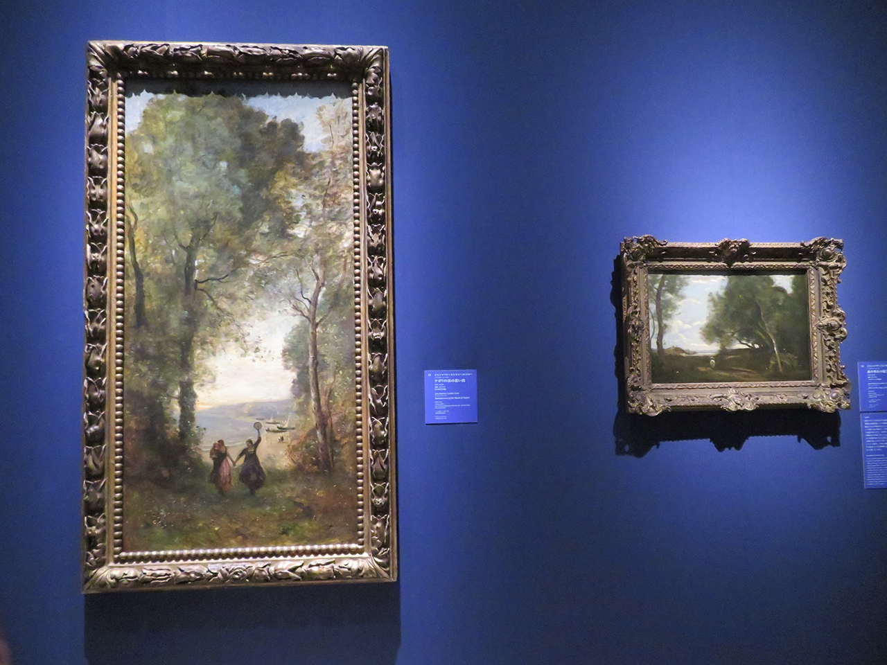 会場風景（以下同様）。左から、ジャン=バティスト・カミーユ・コロー《ナポリの浜の思い出》1870～72年　国立西洋美術館。同《森の外れの騎手》1874/1875年　フォルクヴァング美術館。自然観察に思い出を重ね、詩情溢れる世界を創出
