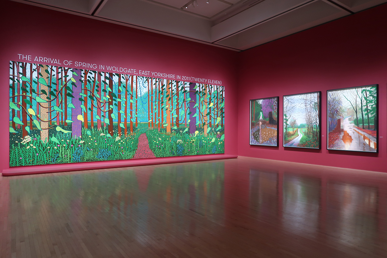 「デイヴィッド・ホックニー展」展示風景、東京都現代美術館、2023年　©︎ David Hockney デイヴィッド・ホックニー〈春の到来　イースト･ヨークシャー、ウォルドゲート2011年〉より　2011年　　左の油彩画は、ポンピドゥー・センター蔵／右のiPadドローイングの3点は、デイヴィッド・ホックニー財団蔵